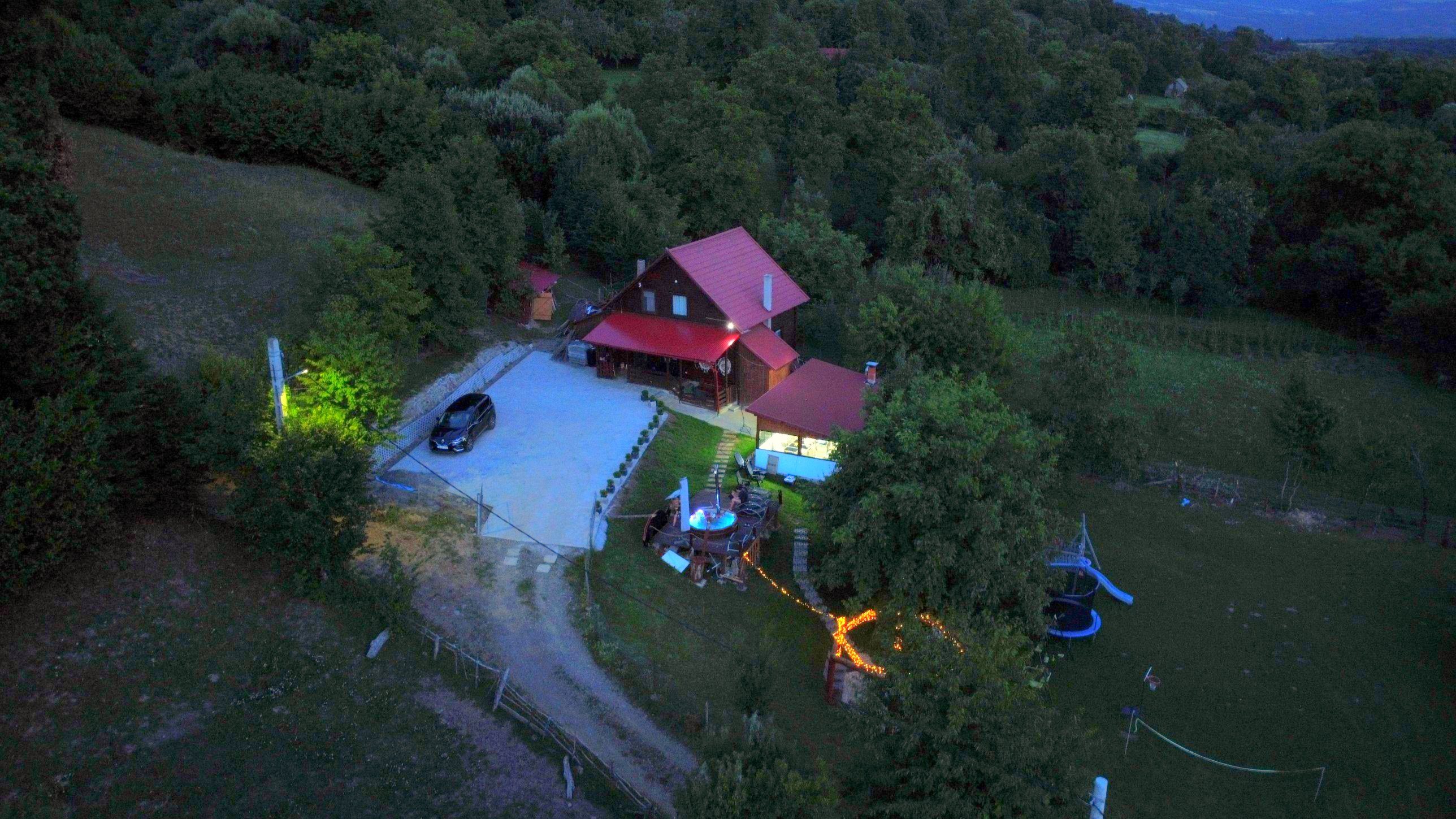 Cabana Casa DeSub Scaun la apus, văzută de sus: casa luminată, ciubărul și ghirlandele de lumini din curte